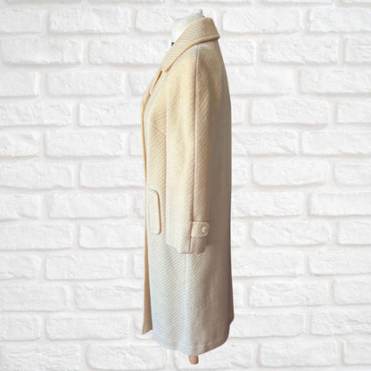 Beige coat on a mannequin against a white brick wall background
