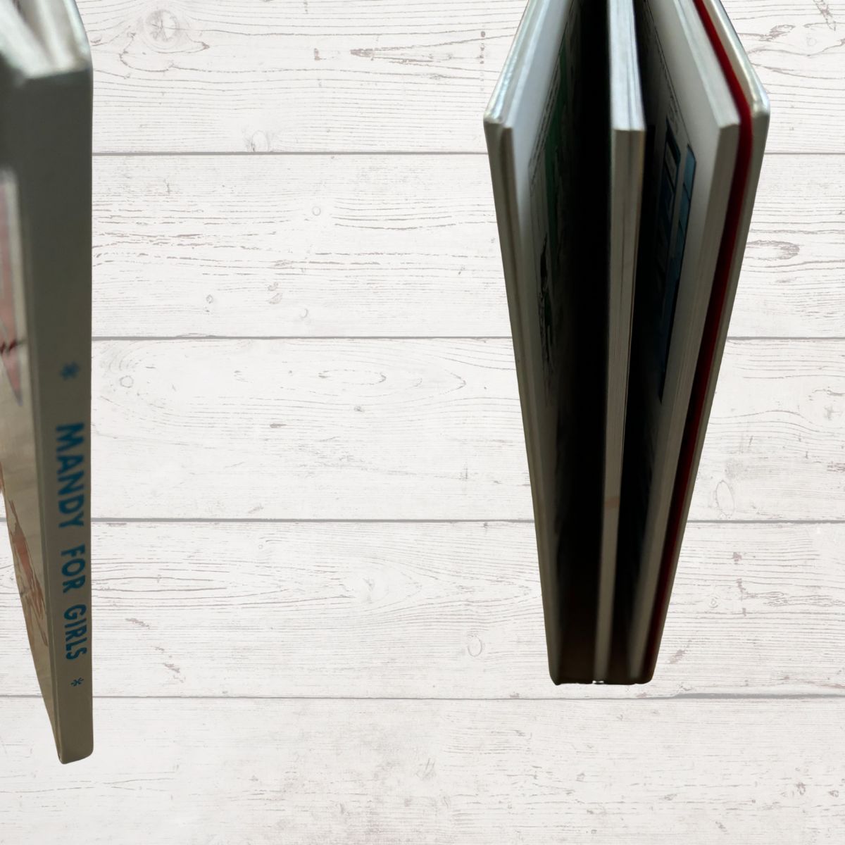 Two books open to pages with text on a light wooden surface