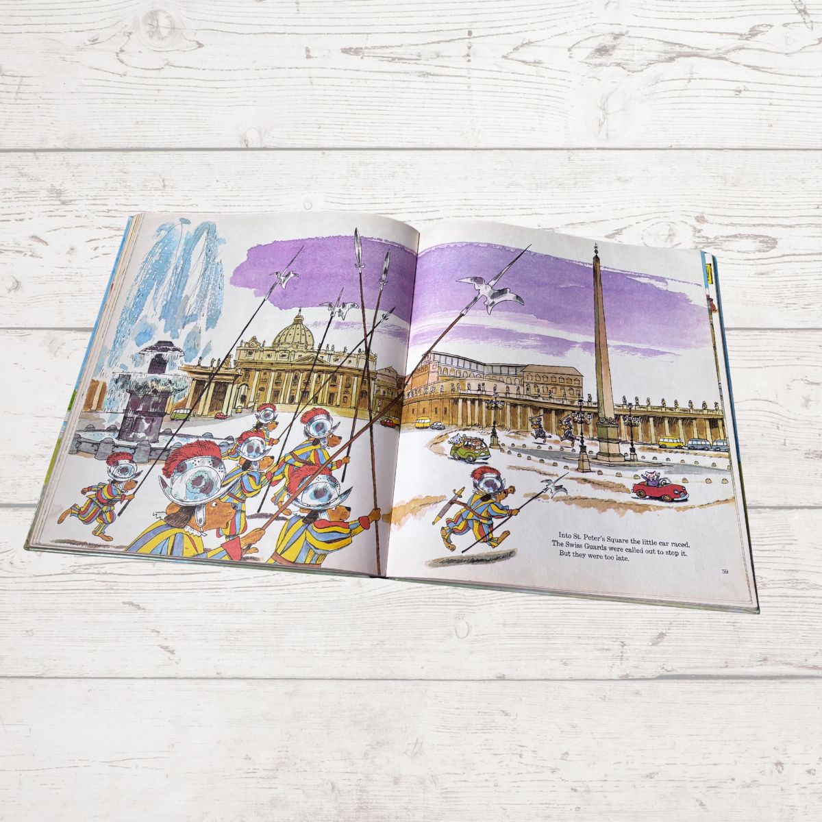 Open book showing illustrations of a cityscape with buildings and characters on a wooden surface