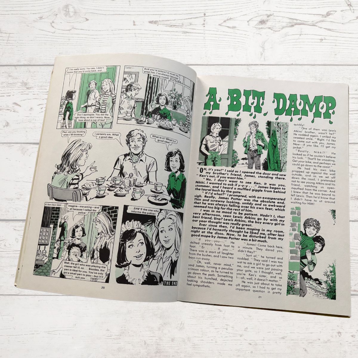 Comic book open to a page with illustrations and text on a wooden surface