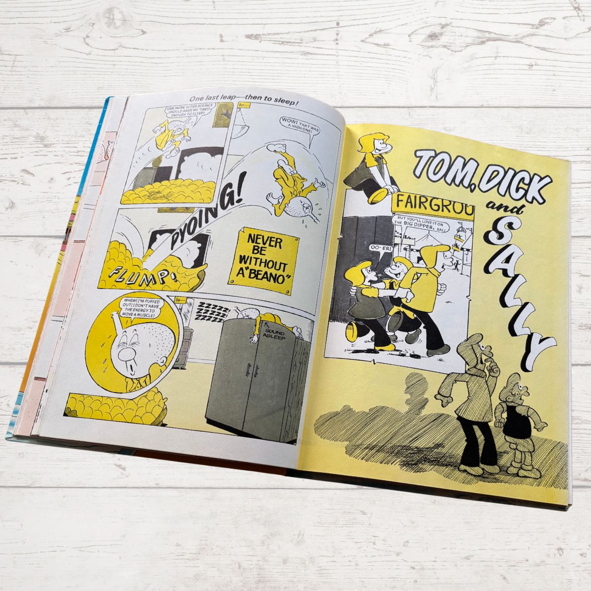 Open book displaying comic strips with characters and text on a wooden surface