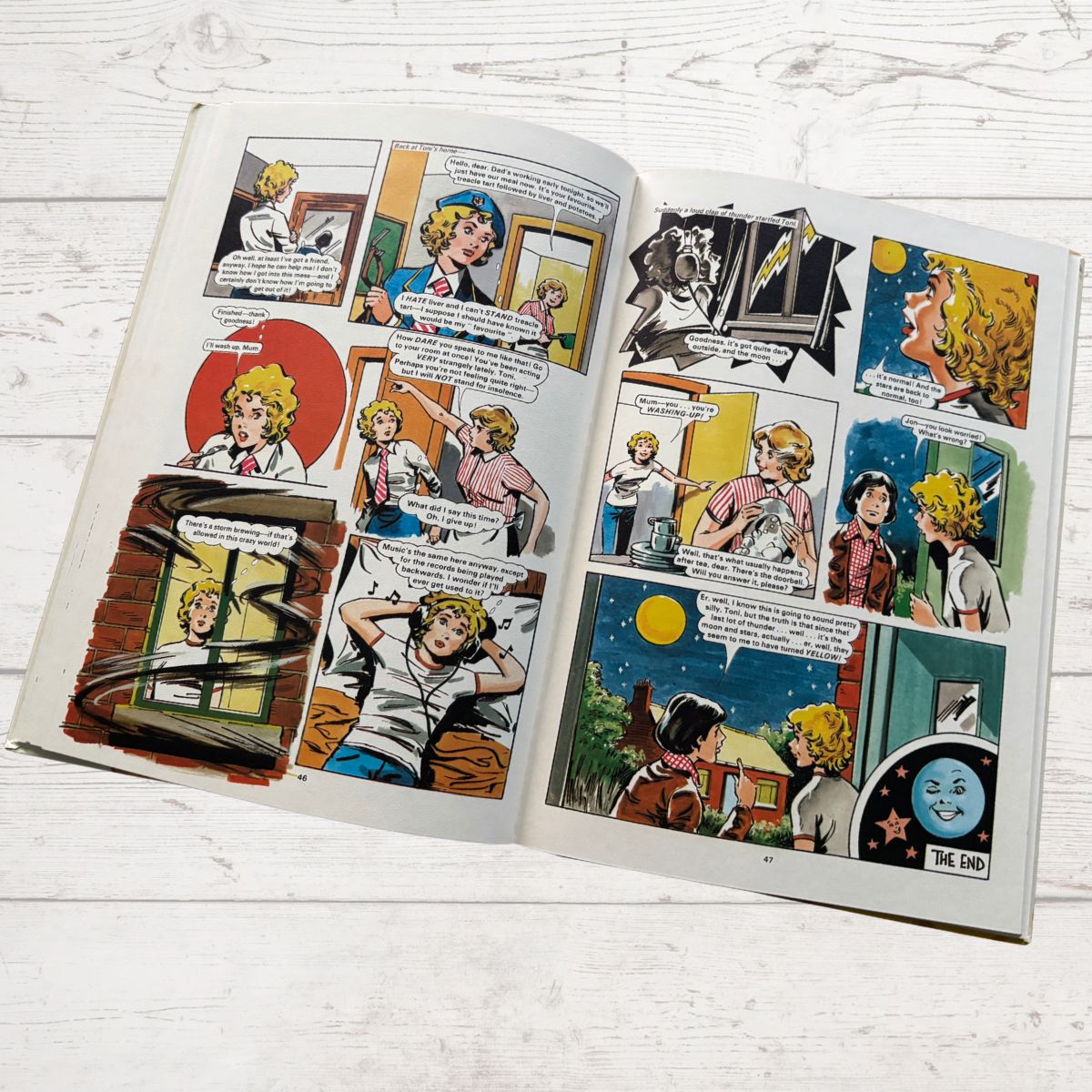 Open comic book with multiple panels on a wooden surface