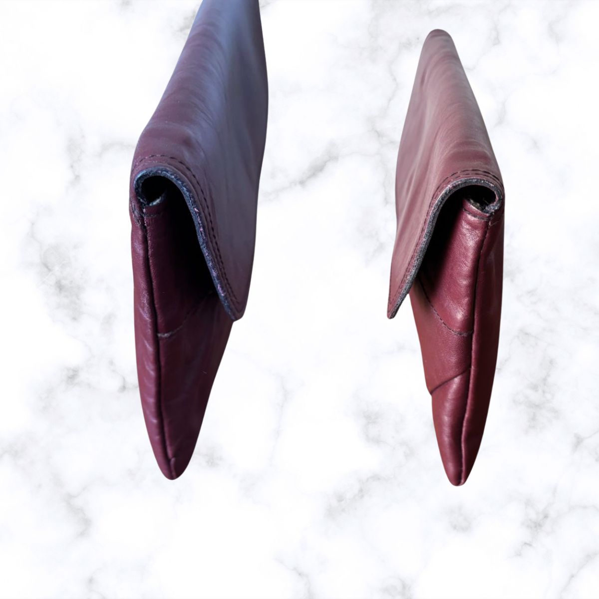 Wine coloured leather bag on a white marble surface