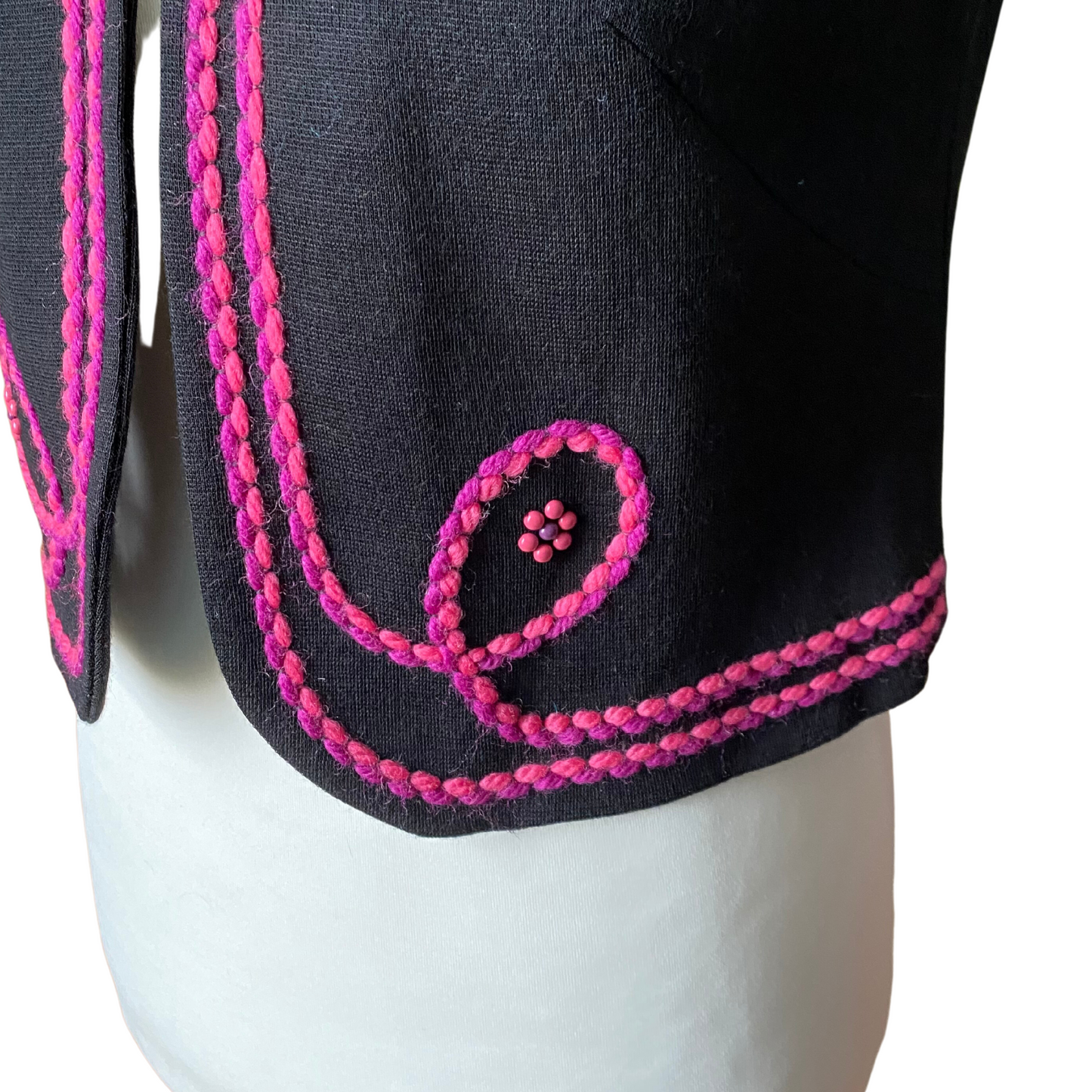 A vintage black waistcoat with 70s flair, highlighted by vibrant pink and purple stitching and intricate beaded flower details.