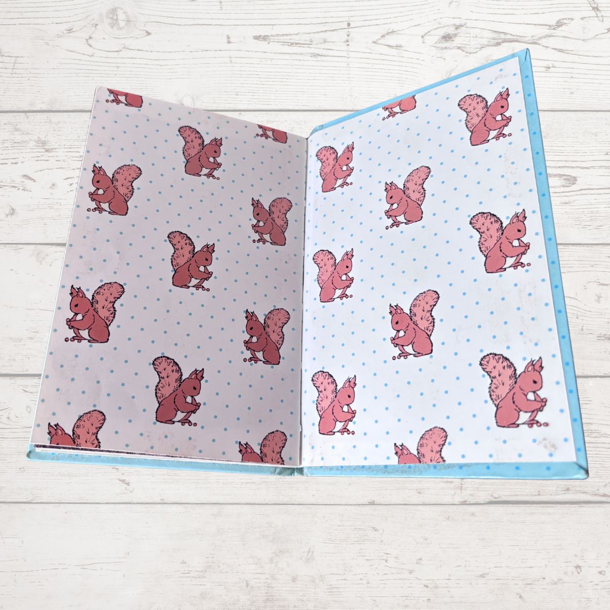 Inside book cover with pink squirrel patterns on a wooden surface