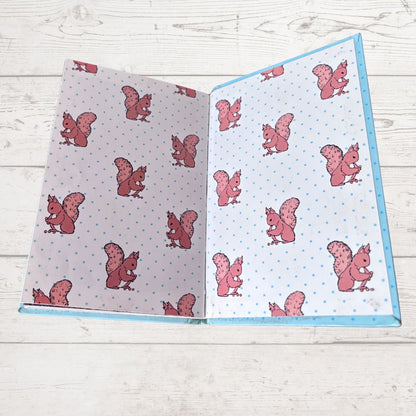 Inside book cover with pink squirrel patterns on a wooden surface