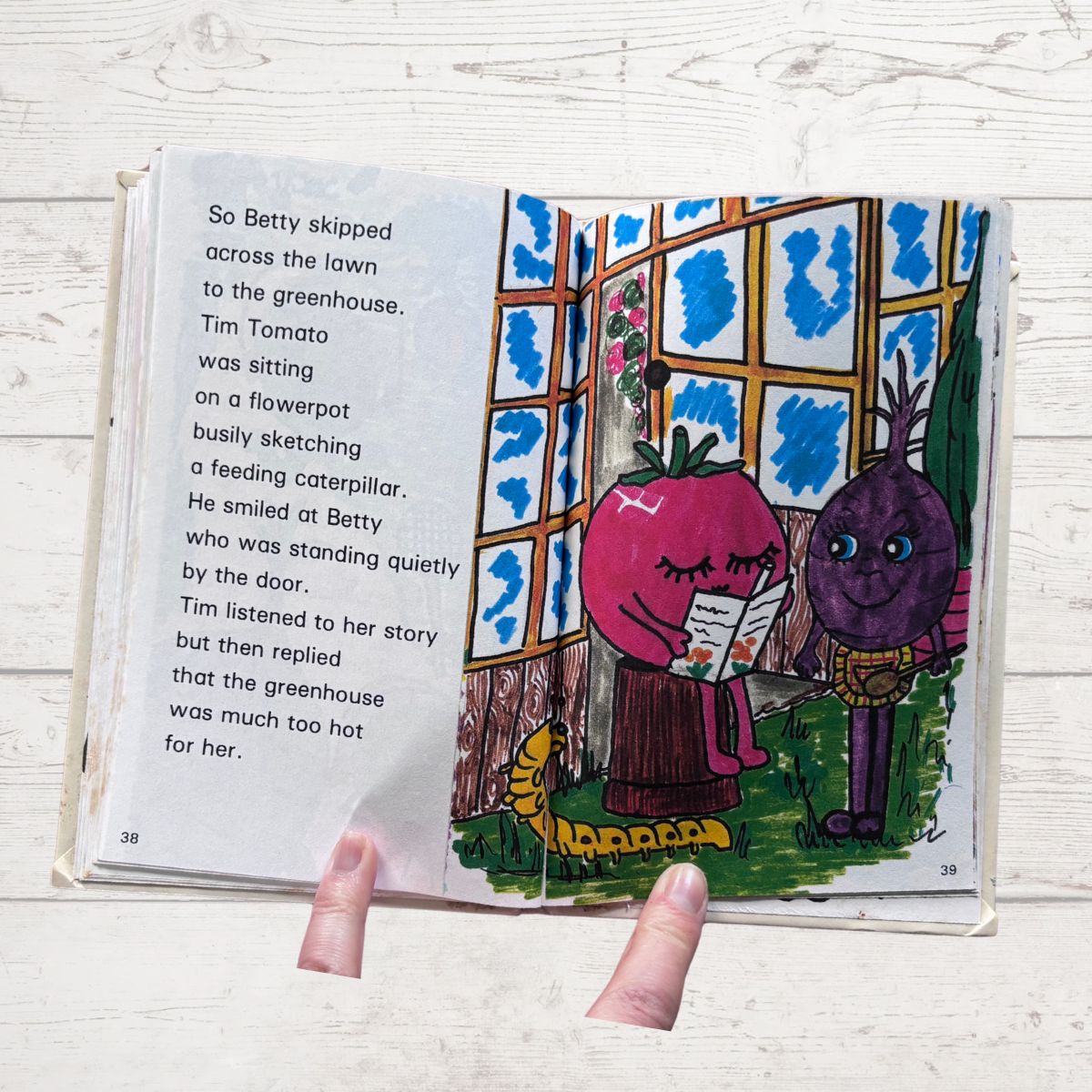 Illustrated book open to a page with characters and text on a wooden surface
