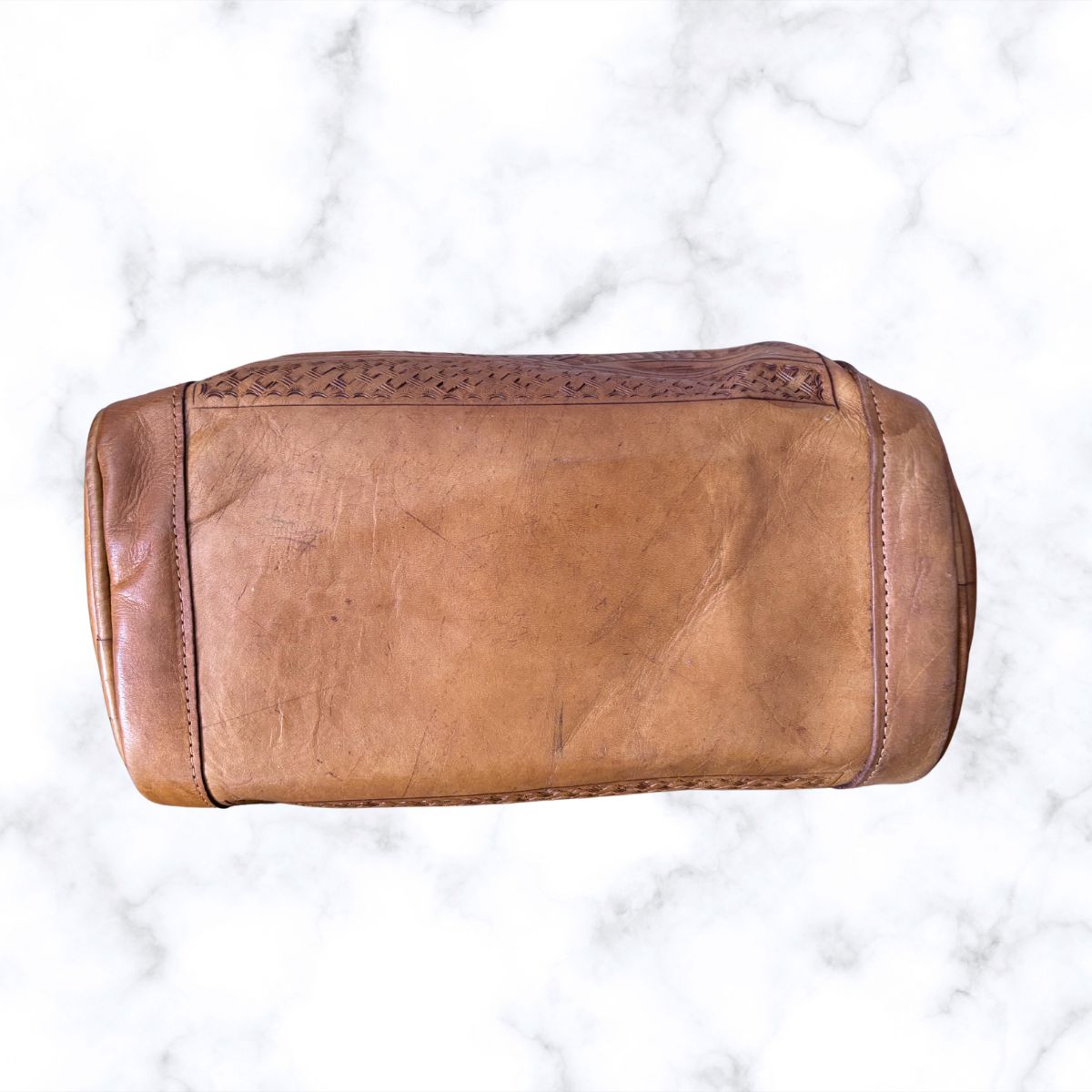 Brown leather toiletry bag on a white marble background