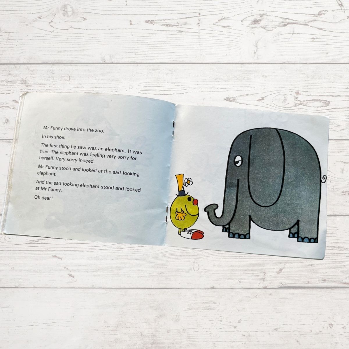 Open book with illustrations of Mr Funny and an elephant on a wooden surface