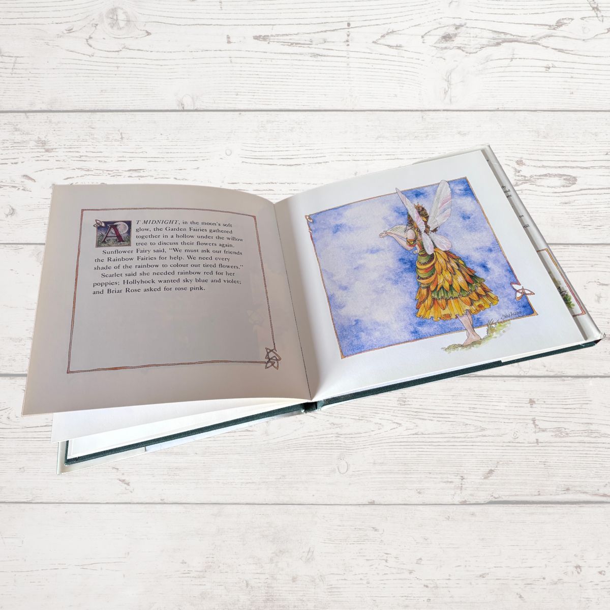 Open book with a colorful illustration of a fairy on a white wooden surface