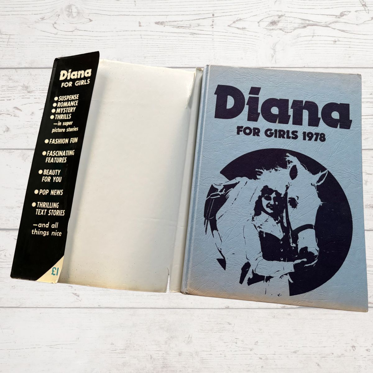 Open book titled 'Diana for Girls 1978' with a horse illustration on a wooden surface.
