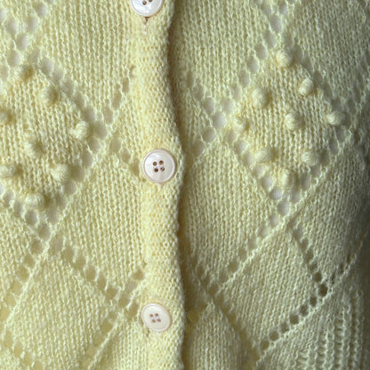 Close-up of a light yellow  knitted cardigan with button details