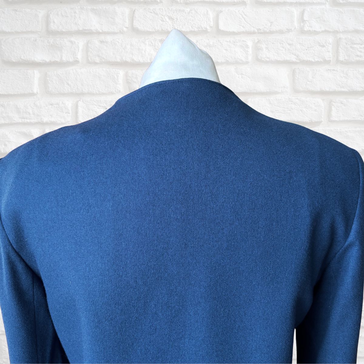 Blue jacket  on a mannequin against a white brick wall background