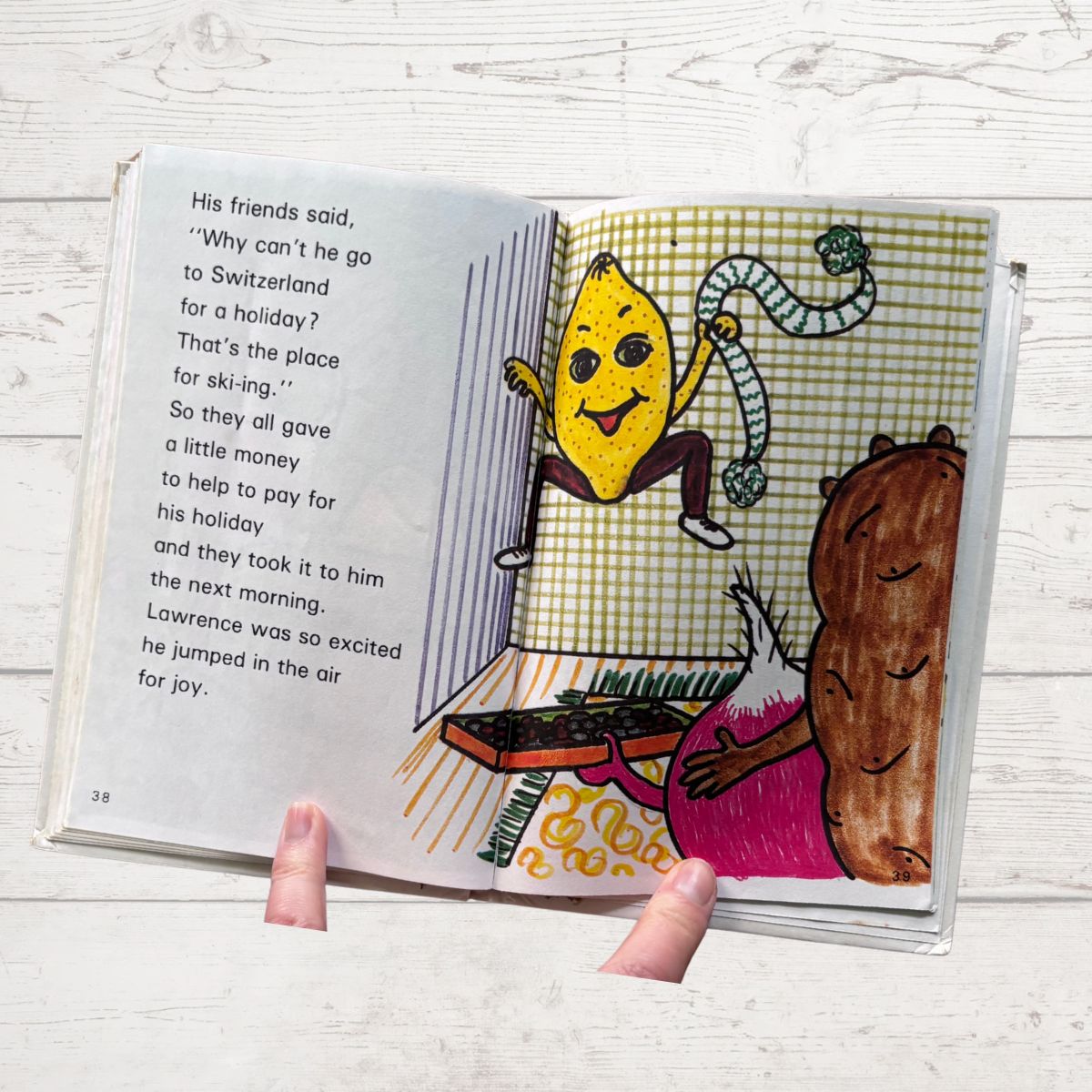 Open book with colorful illustrations of a lemon character and a bear on a wooden surface