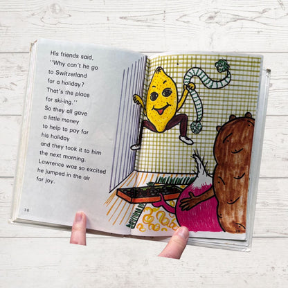 Open book with colorful illustrations of a lemon character and a bear on a wooden surface