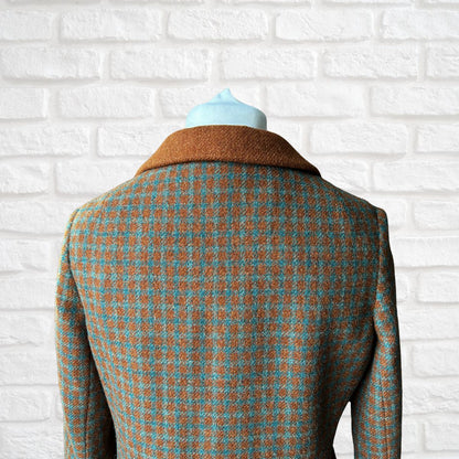 Houndstooth patterned coat on a mannequin against a white brick wall.