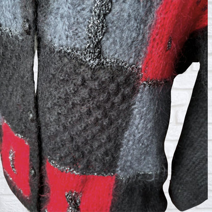 Close up of mixed red, black, silver sparkle mixed textured yarn on a cardigan 