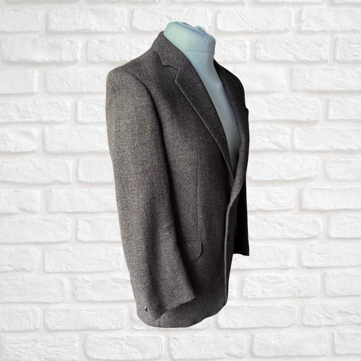 Brown  blazer on a mannequin against a white brick wall background