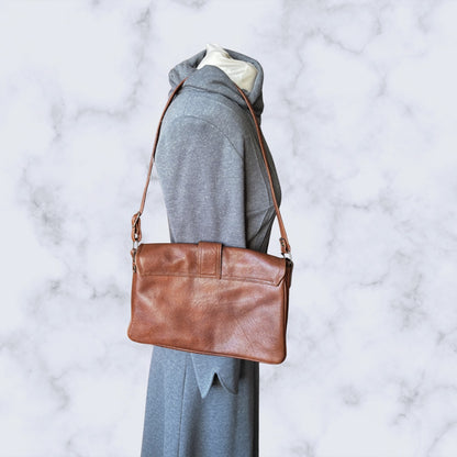 Brown vinyl  shoulder bag on a mannequin against a marble background
