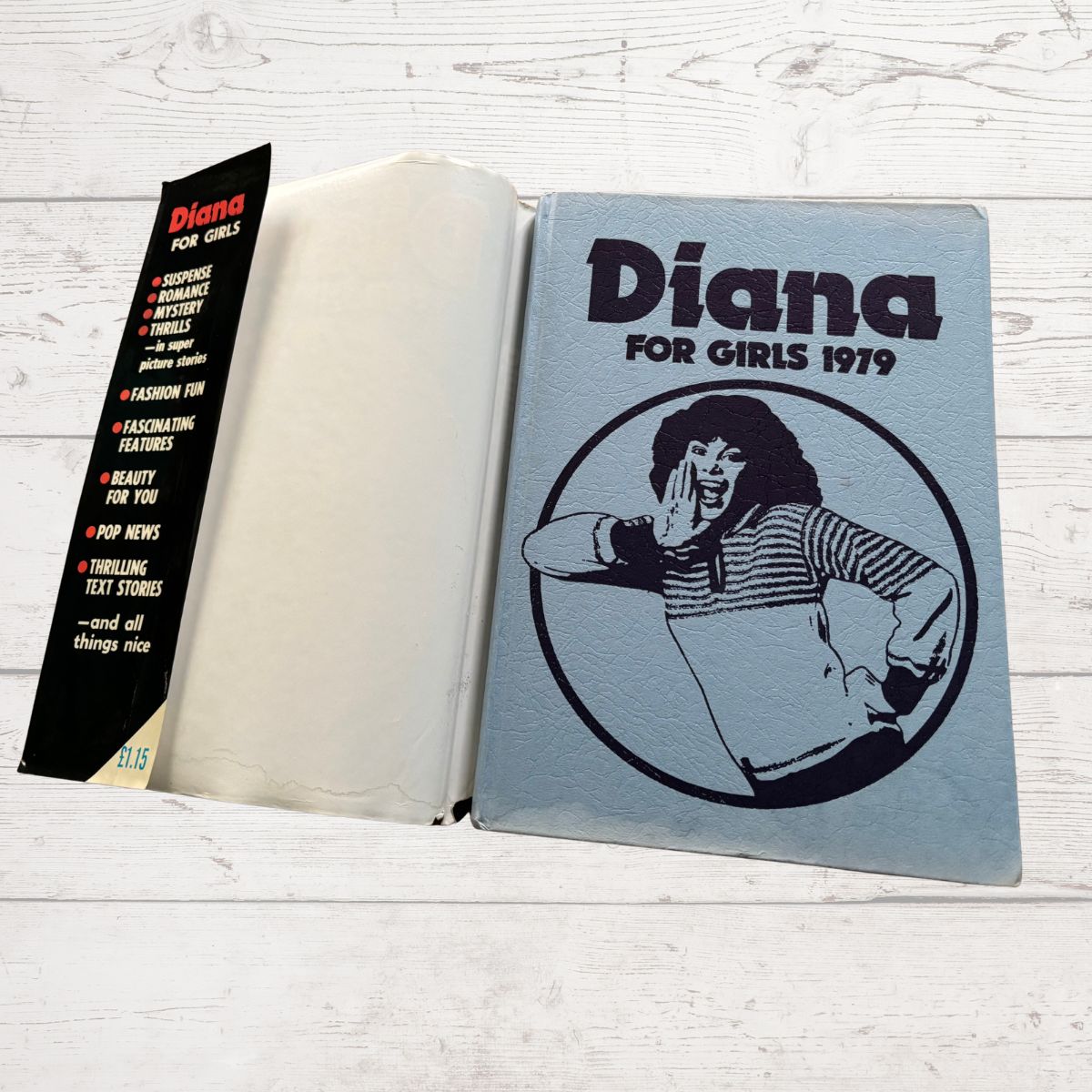 Vintage book  titled 'Diana for Girls 1979' on a wooden surface with a bookmark.