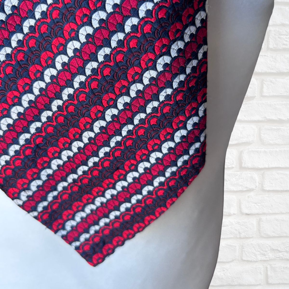 Patterned tie on a mannequin with a white brick wall background