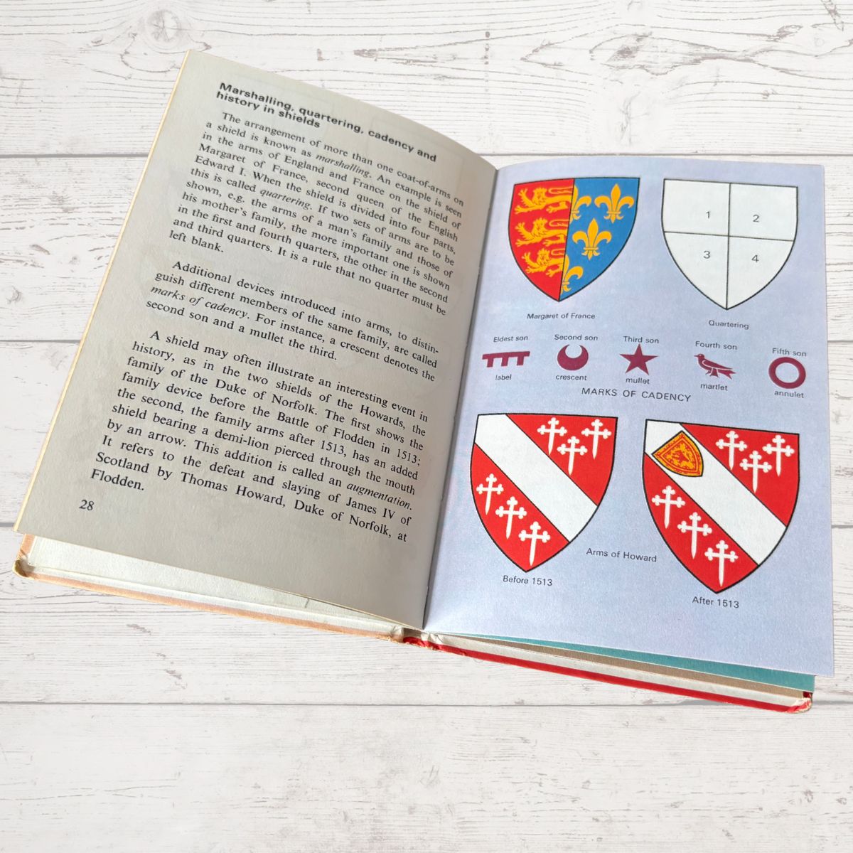 Open book on a wooden surface with illustrations of coats of arms