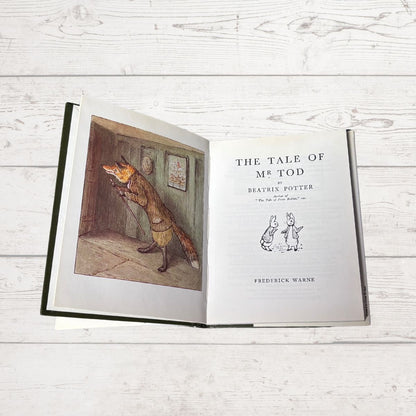 Open book titled 'The Tale of Mr. Tod' by Beatrix Potter on a wooden surface