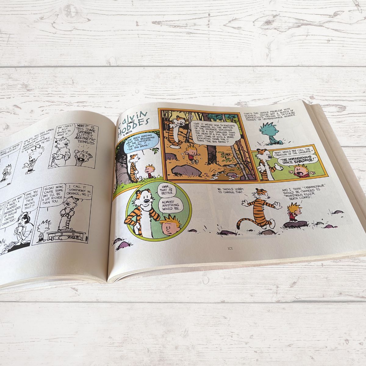 Open book with comic pages featuring cartoon characters on a light wooden surface