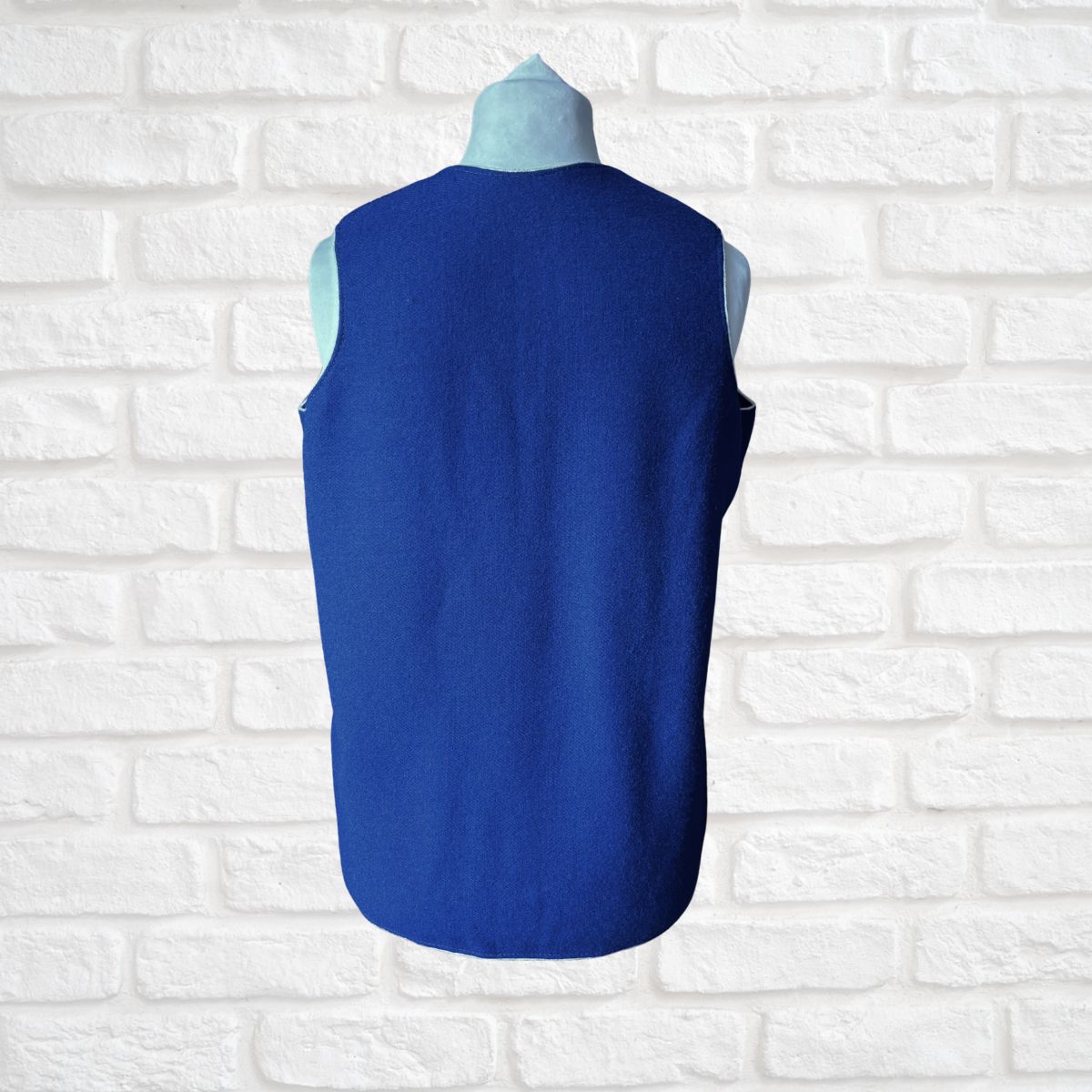 Blue vest on a mannequin against a white brick wall background