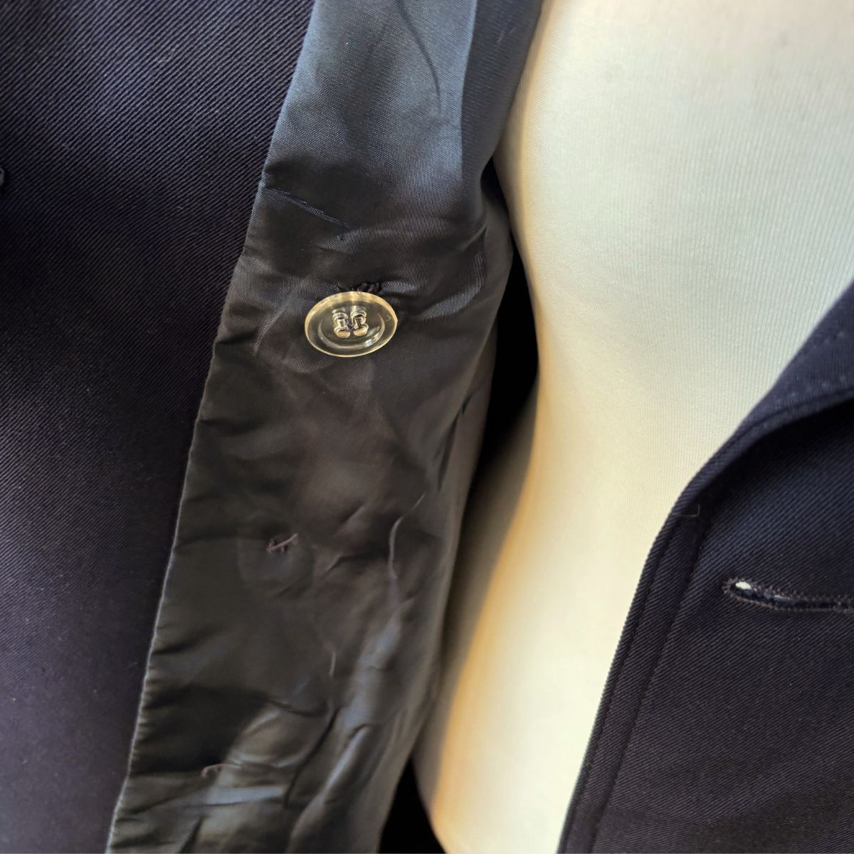 Close-up of a dark blue coat with hidden inside button on a neutral background