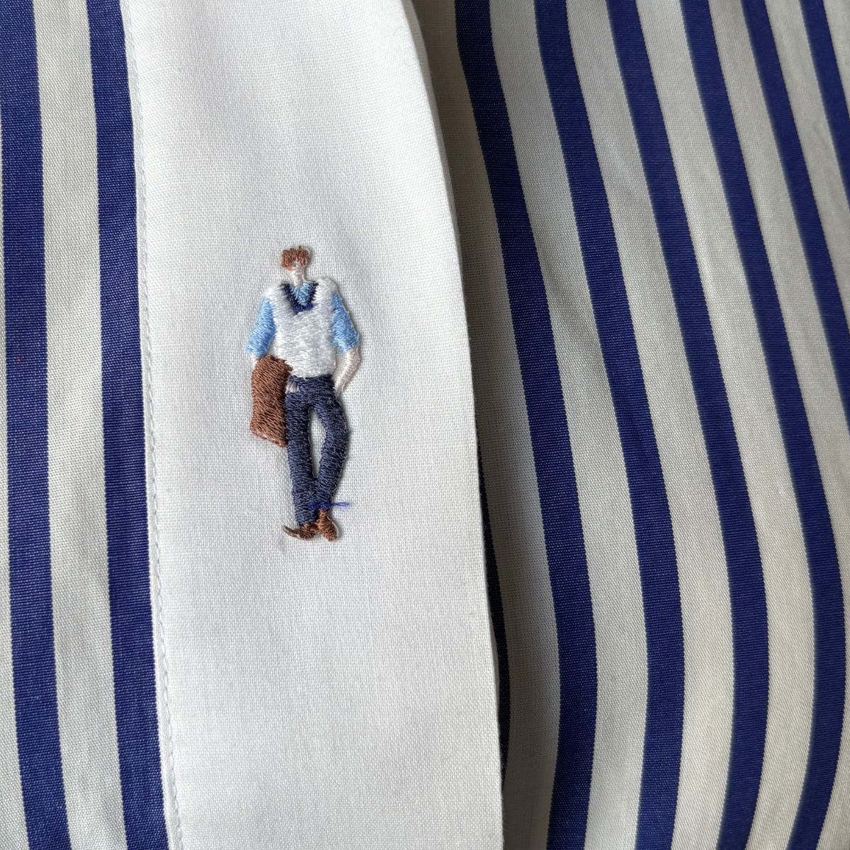 Embroidered design of a person on a blue and white striped fabric