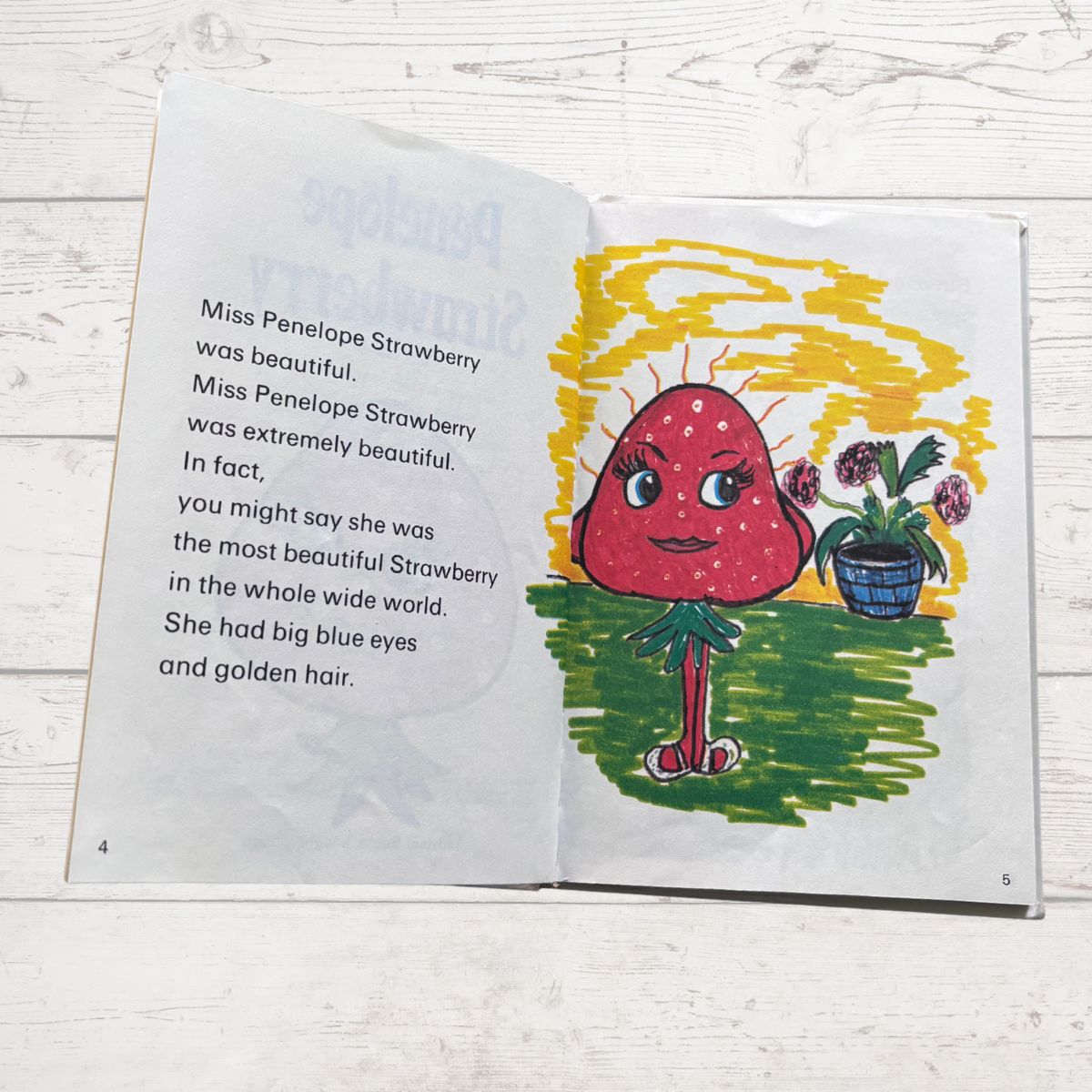 Colourfully illustrated childrens book featuring a smiling strawberry on a white surface 