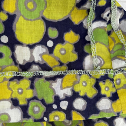 Floral patterned fabric with yellow, green, and white flowers on a dark blue background.