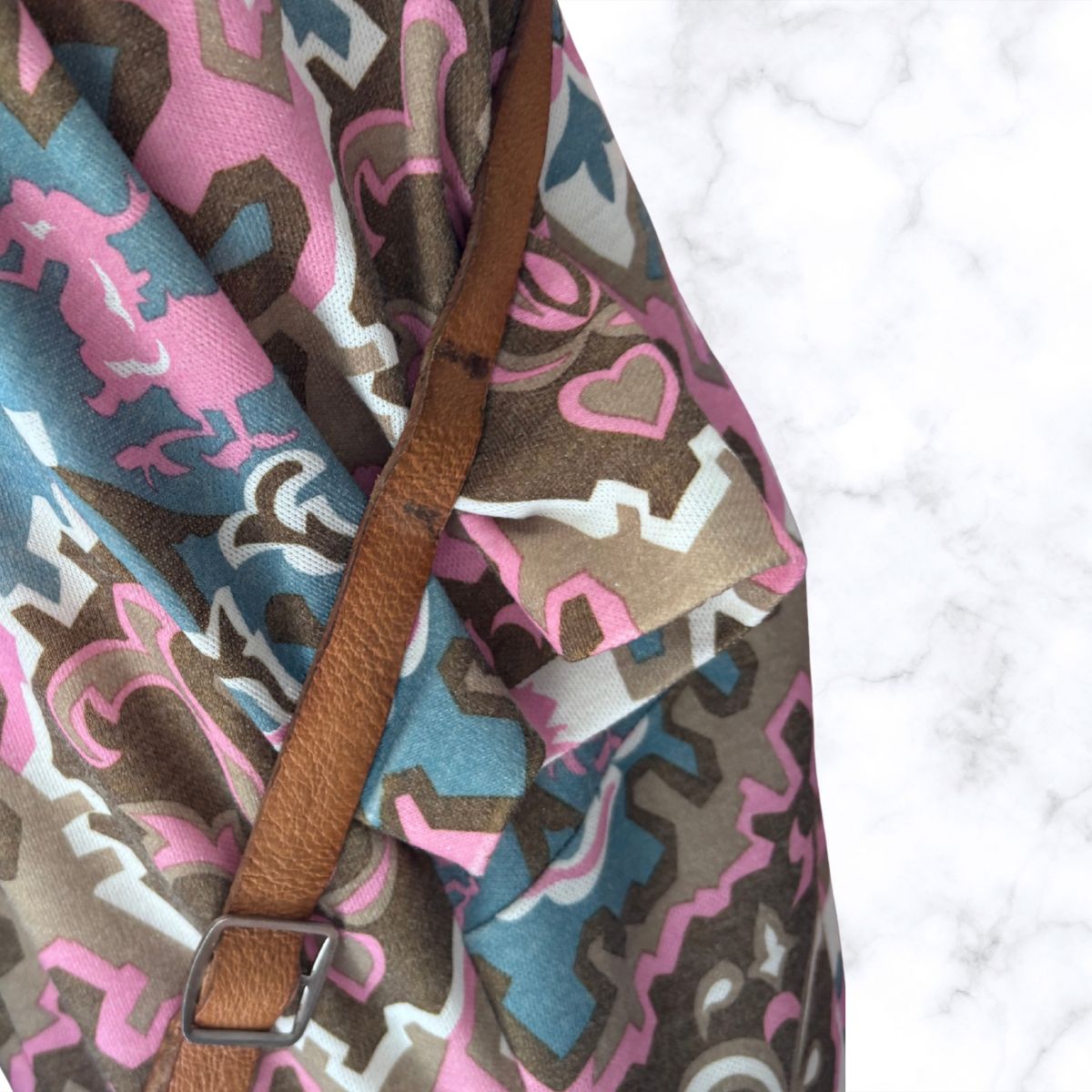 Fabric with pink and brown pattern and a brown strap on a white background