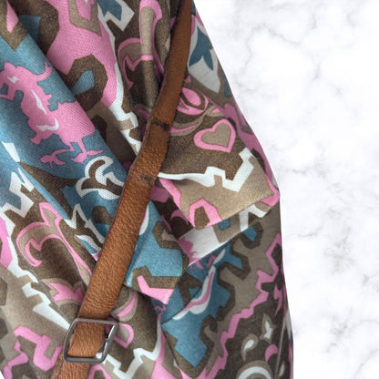 Fabric with pink and brown pattern and a brown strap on a white background