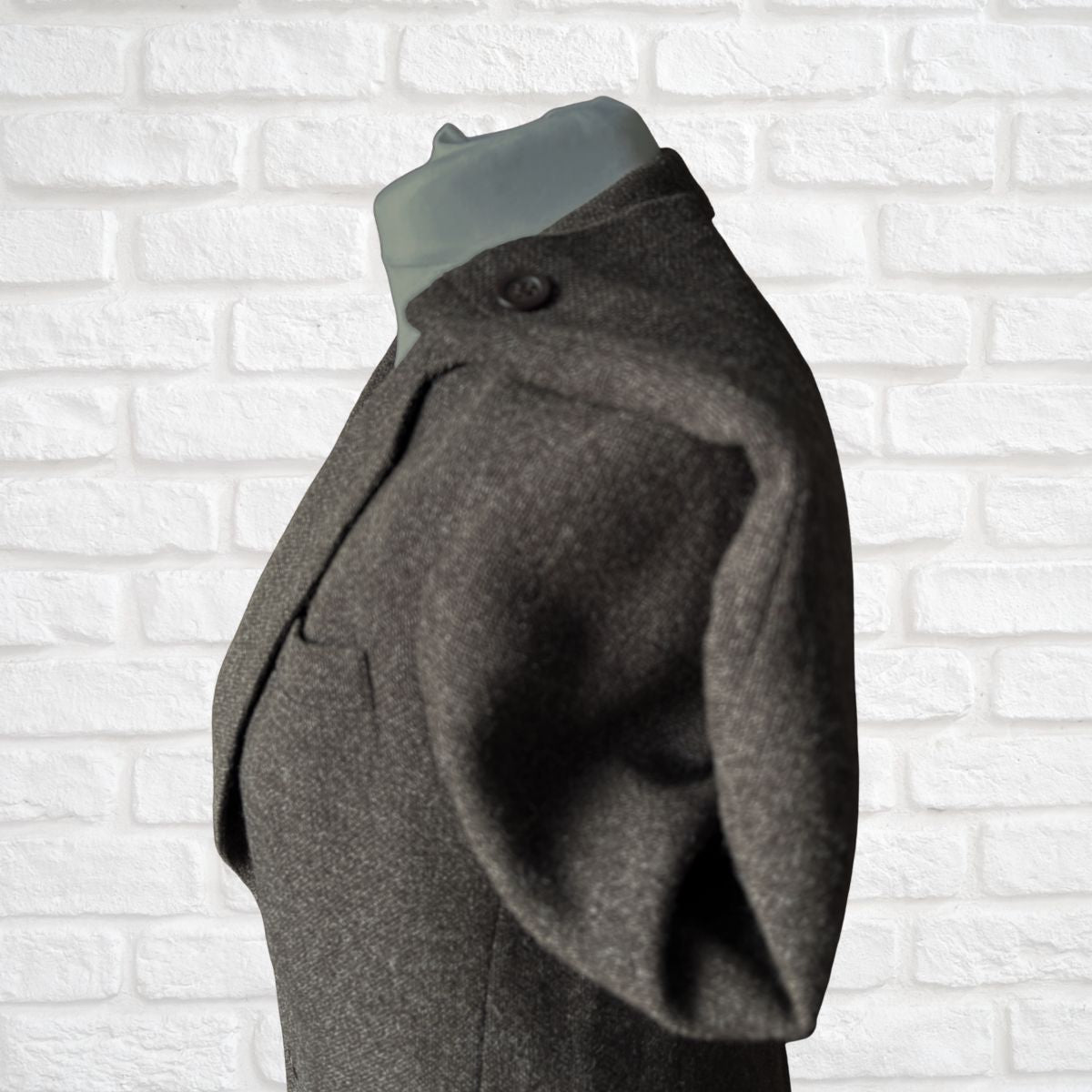 Brown jacket on a mannequin against a white brick wall background