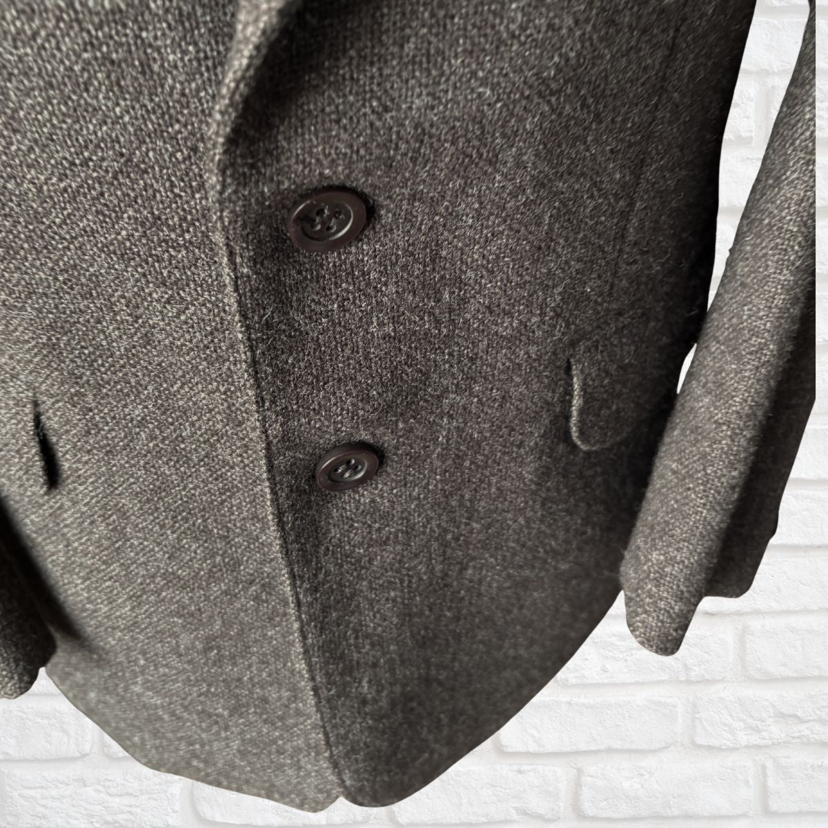 Close-up of a brown textured coat with buttons on a white background