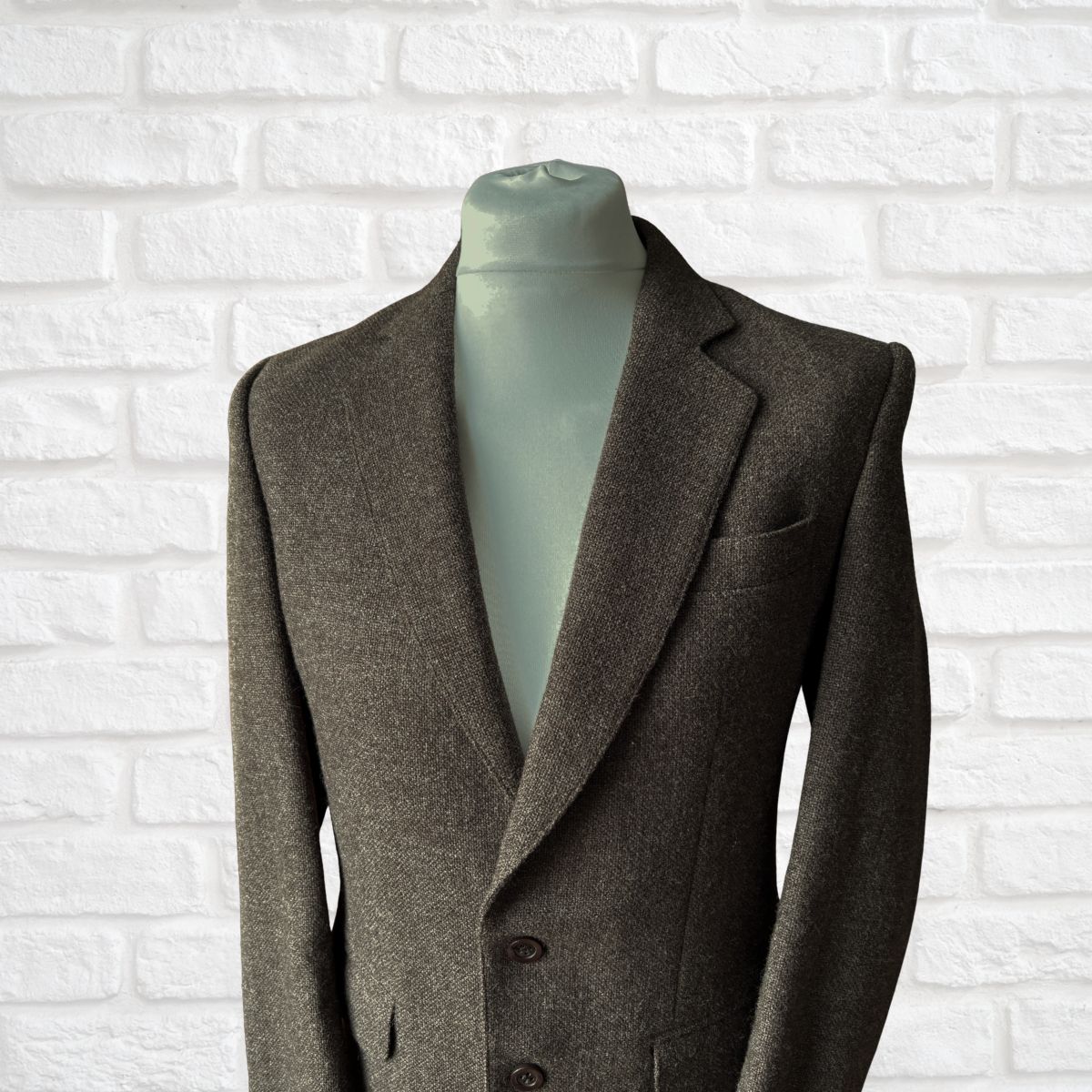Brown suit jacket on a mannequin against a white brick wall background