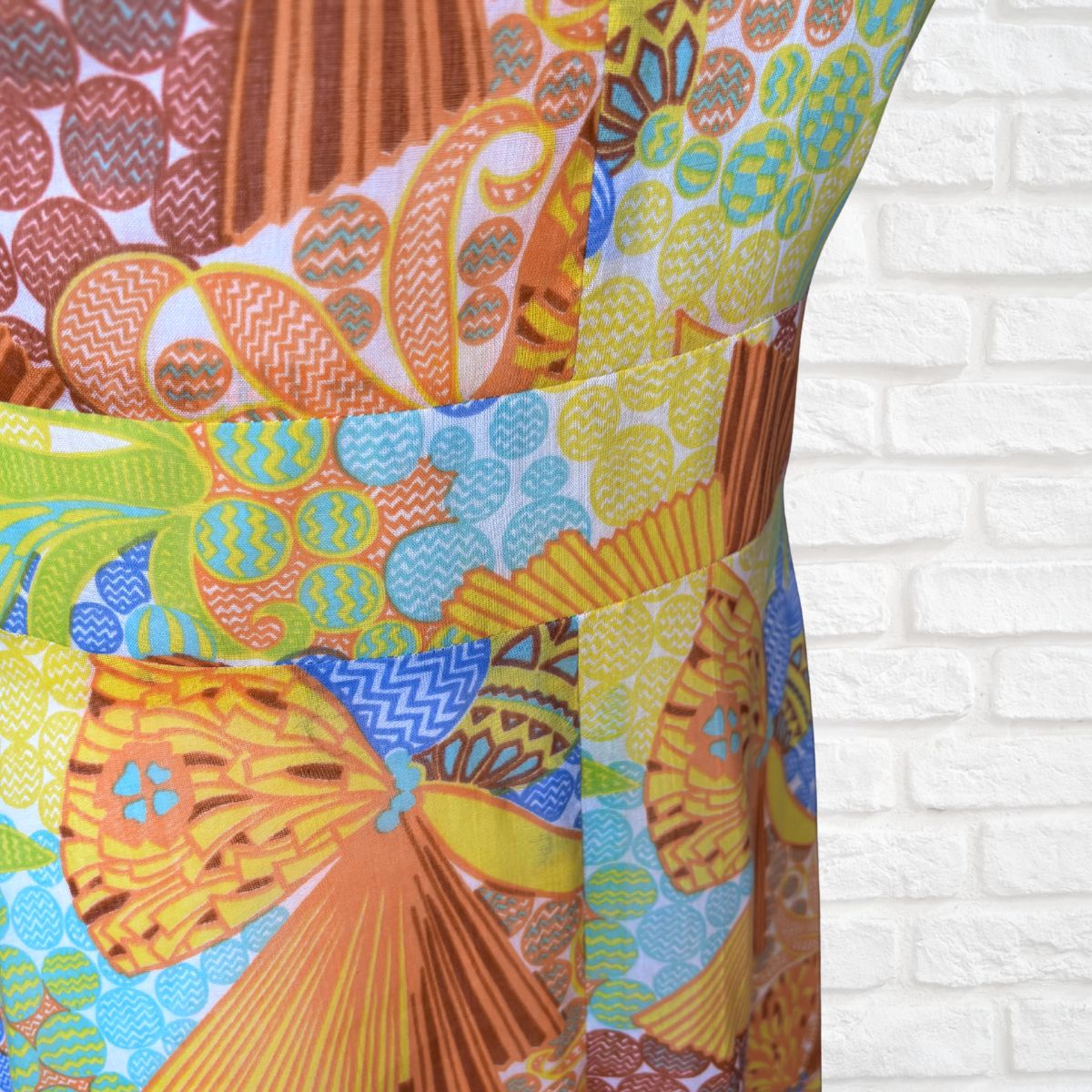 Colorful patterned fabric with geometric designs on a white brick wall background