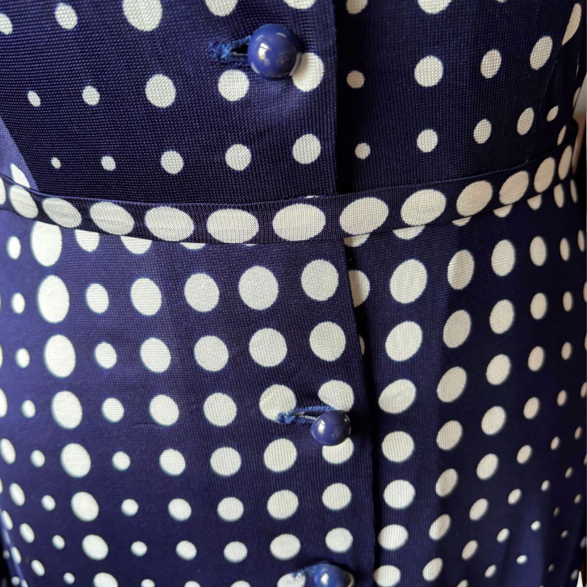 Navy blue fabric with white polka dots and blue buttons