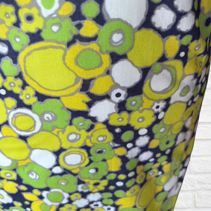 Close-up of a fabric with a colorful floral pattern featuring yellow, green, and white on a blue background.
