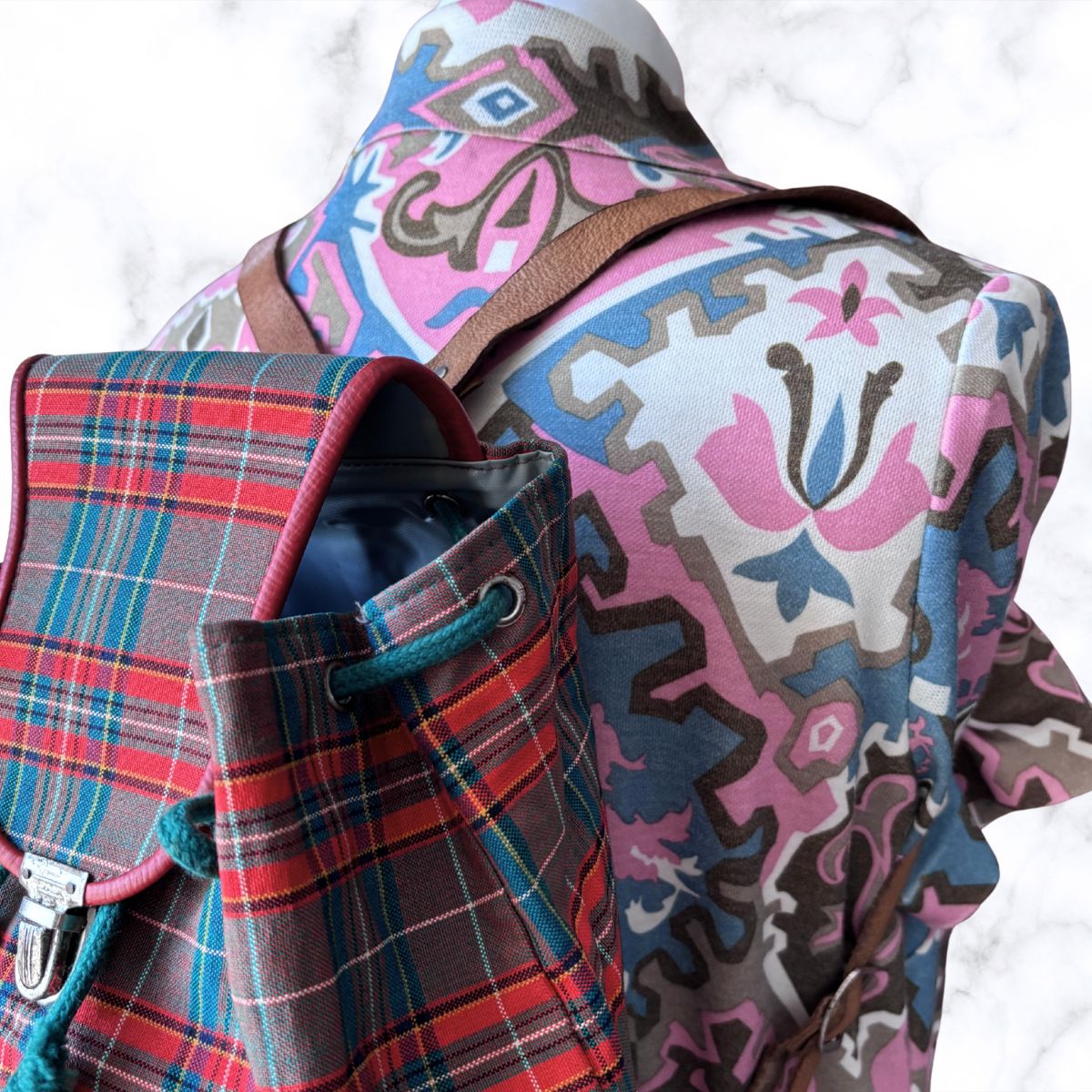 Plaid backpack and patterned jacket on a white background