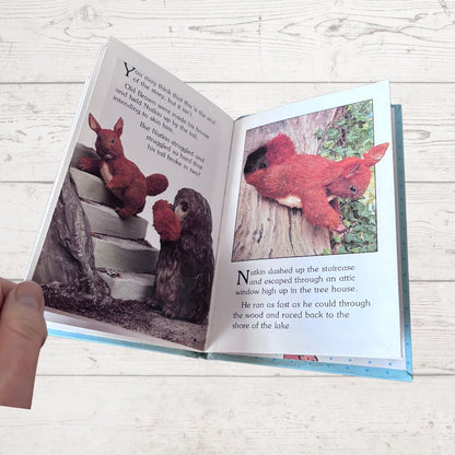 Open book with illustrations of red squirrels on a wooden surface