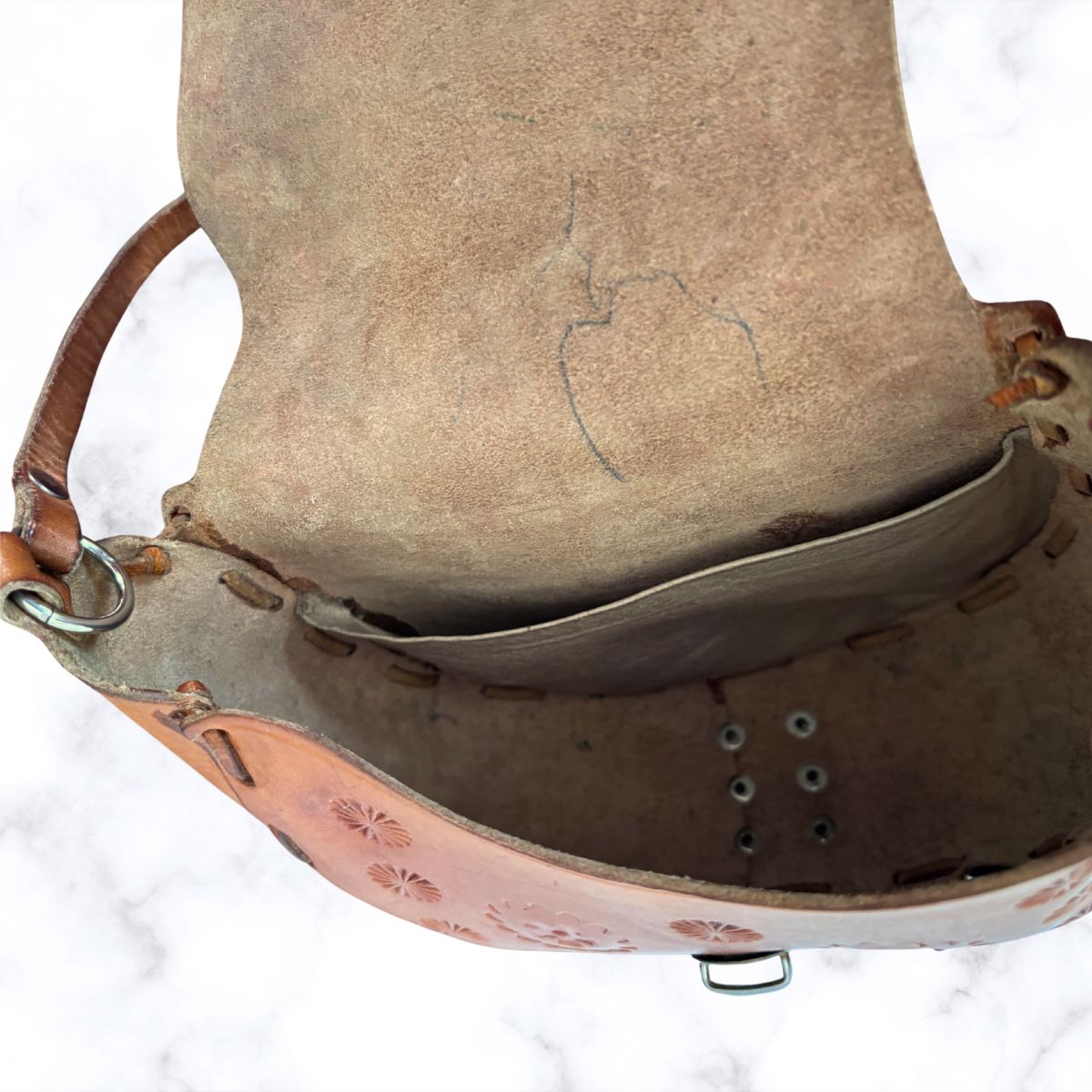 Close-up of inside of leather bag with floral patterns on a white background