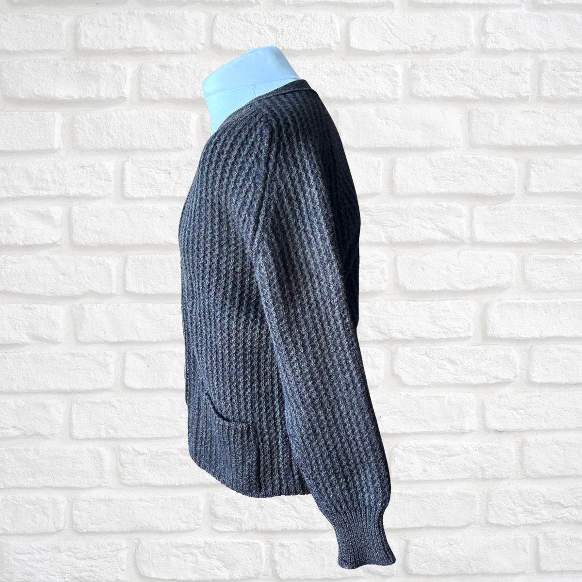 Brown knitted cardigan on a mannequin against a white brick wall background