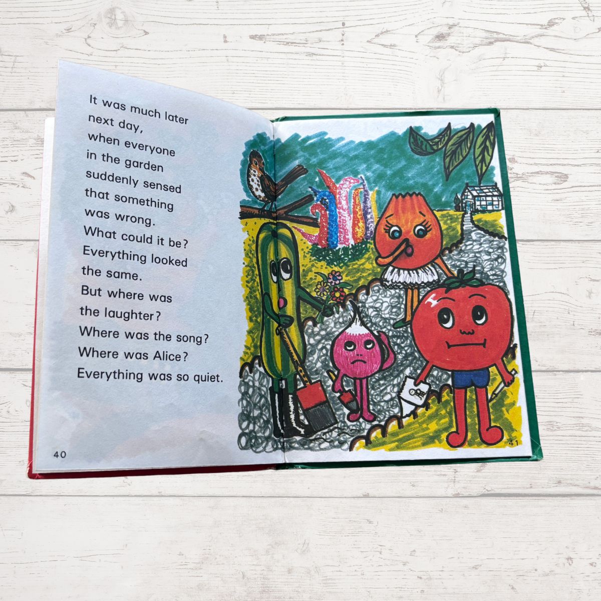 Open book with colorful illustration of characters in a garden on a wooden surface