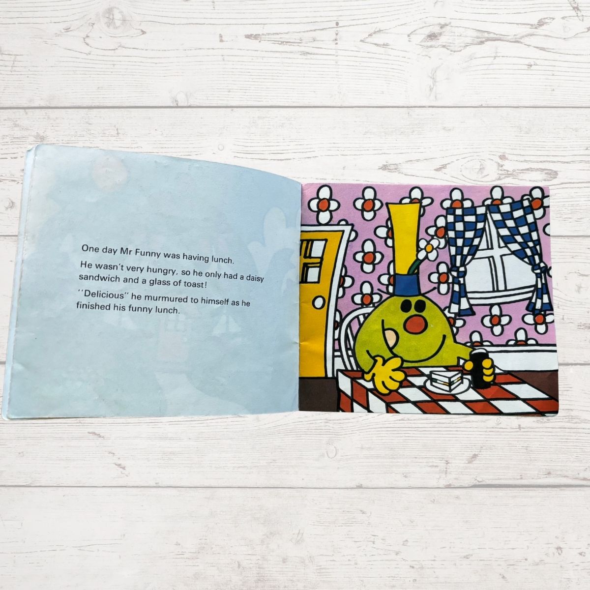 Open book with a colorful illustration of a character and text on a wooden surface