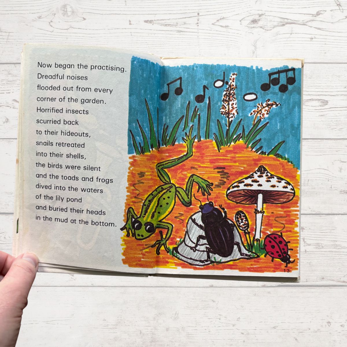 Open book with colorful illustration of a garden scene and text on a wooden surface