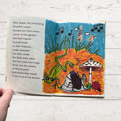 Open book with colorful illustration of a garden scene and text on a wooden surface