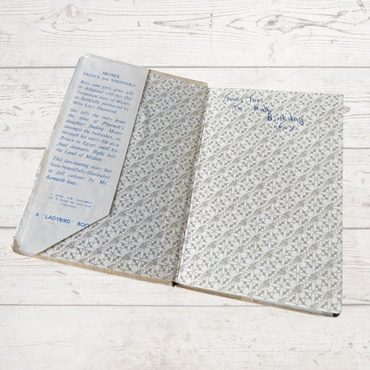 Open book with text and patterned cover on a wooden surface
